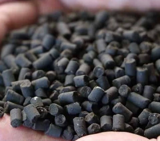 A Person Holding A Pile Of Black Fertilizer Pellets In Their Hands